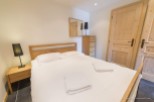 Cozy bedroom with a comfortable double bed, wooden furniture, and plenty of natural light.