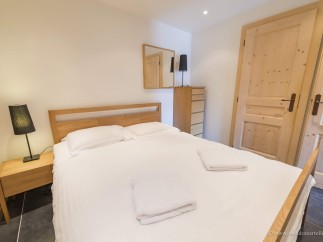 Cozy bedroom with a comfortable double bed, wooden furniture, and plenty of natural light.