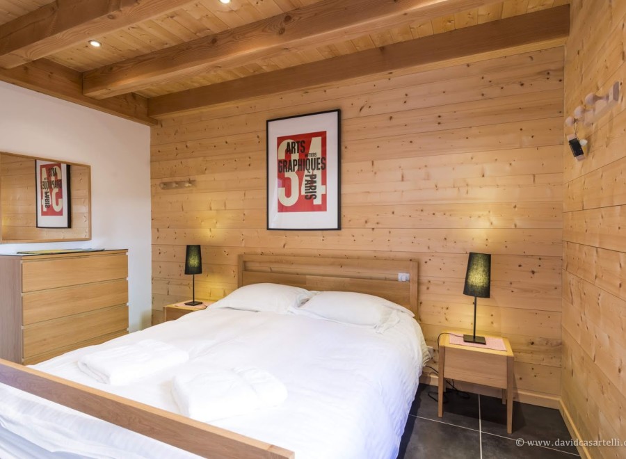 Cozy bedroom with wood paneling and exposed beams.