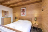 Cozy bedroom with wood paneling and exposed beams.
