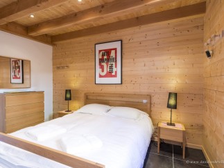 Cozy bedroom with wood paneling and exposed beams.