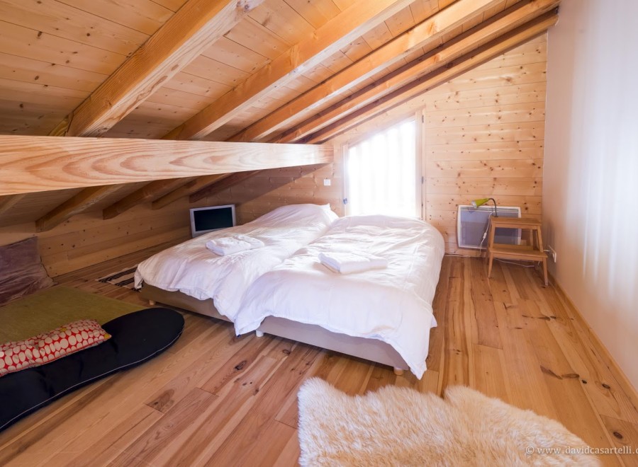Cozy attic bedroom with twin beds, wooden beams, and a wood floor.