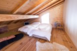 Cozy attic bedroom with twin beds, wooden beams, and a wood floor.