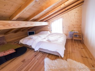 Cozy attic bedroom with twin beds, wooden beams, and a wood floor.