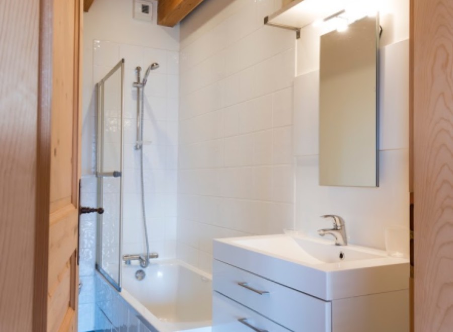 Charming bathroom with wooden beams, white tile, and a modern vanity.