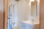 Charming bathroom with wooden beams, white tile, and a modern vanity.