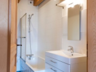 Charming bathroom with wooden beams, white tile, and a modern vanity.