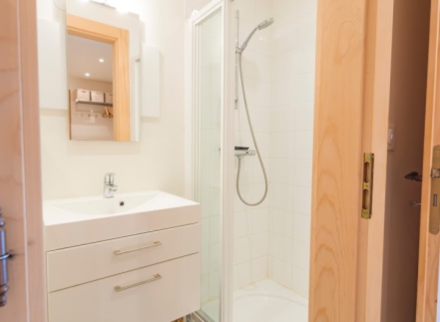 This modern bathroom boasts a sleek white vanity with ample storage, a spacious shower enclosure, and stylish matte black floor tiles.