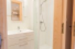 This modern bathroom boasts a sleek white vanity with ample storage, a spacious shower enclosure, and stylish matte black floor tiles.
