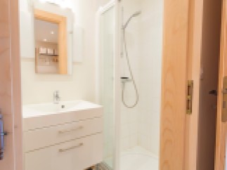 This modern bathroom boasts a sleek white vanity with ample storage, a spacious shower enclosure, and stylish matte black floor tiles.