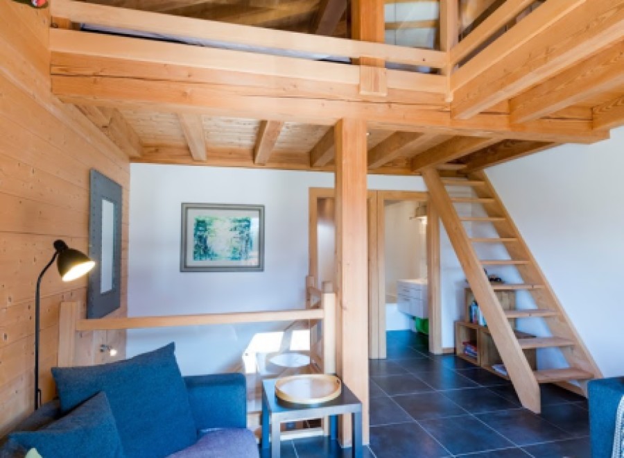 This stunning chalet boasts a spacious open-plan living area with a cozy sofa and a unique loft bedroom.