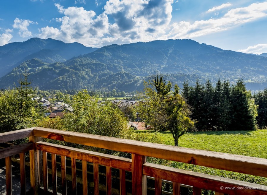 Mountain view from a balcony with wooden railings.