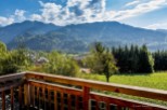 Mountain view from a balcony with wooden railings.