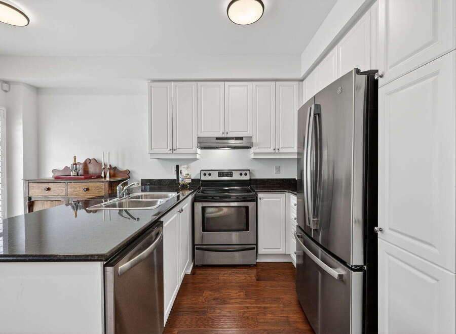 This stunning kitchen boasts modern stainless steel appliances, including a refrigerator, oven, and dishwasher, complemented by sleek black countertops.