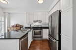 This stunning kitchen boasts modern stainless steel appliances, including a refrigerator, oven, and dishwasher, complemented by sleek black countertops.