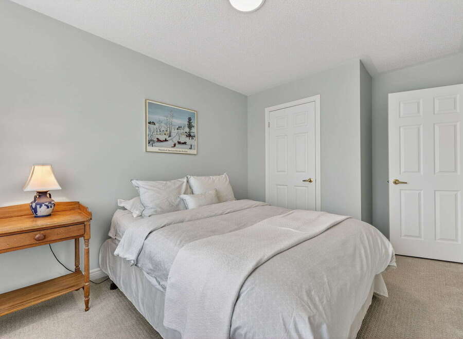 This cozy bedroom offers a serene retreat with its soft, neutral color palette and ample natural light.