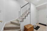 This inviting entryway features a beautiful staircase with carpeted steps and a classic white railing.