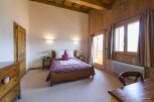 Cozy chalet bedroom with wooden beams, plaid bedding, and stunning mountain views.