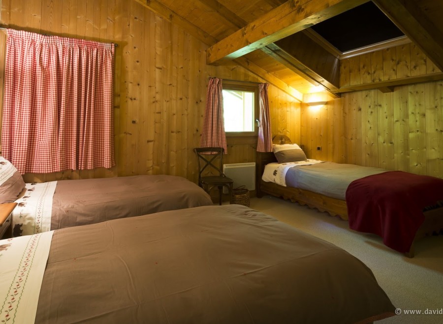 Cozy chalet bedroom with twin beds and a single bed, perfect for families or groups.