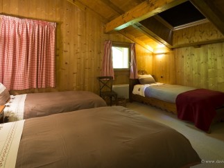 Cozy chalet bedroom with twin beds and a single bed, perfect for families or groups.