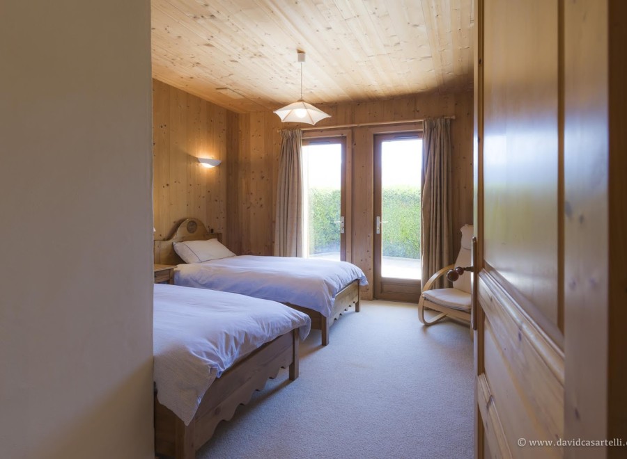 Cozy chalet bedroom with twin beds, wooden walls, and access to a private garden.