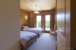 Cozy chalet bedroom with twin beds, wooden walls, and access to a private garden.