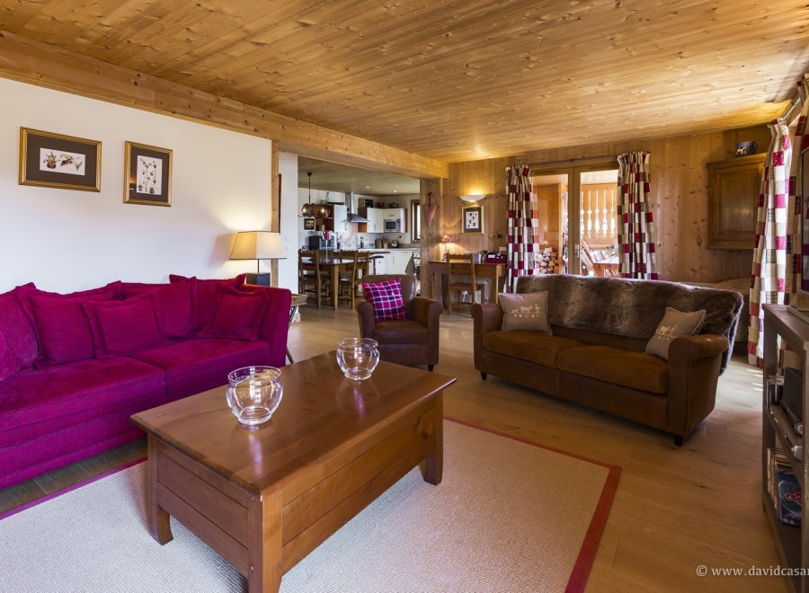 This stunning chalet boasts a spacious living area with plush seating, a cozy wooden interior, and large windows offering ample natural light.