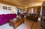 This stunning chalet boasts a spacious living area with plush seating, a cozy wooden interior, and large windows offering ample natural light.