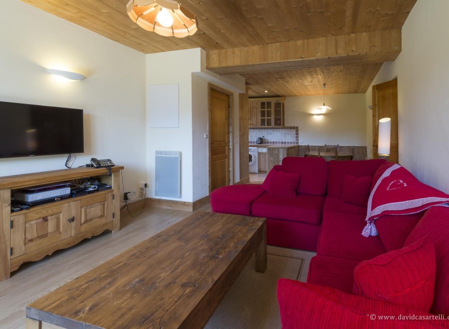 Cozy living room with a wooden interior, featuring a comfortable red couch and a flat-screen TV.