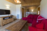 Cozy living room with a wooden interior, featuring a comfortable red couch and a flat-screen TV.