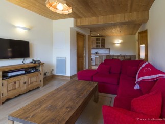 Cozy living room with a wooden interior, featuring a comfortable red couch and a flat-screen TV.