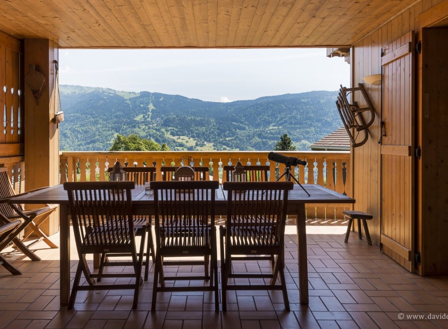 Mountain view dining on a wooden deck with folding chairs and a telescope.