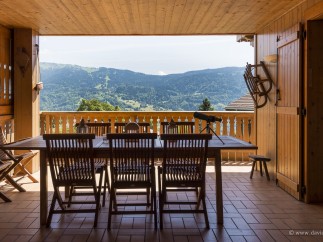 Mountain view dining on a wooden deck with folding chairs and a telescope.