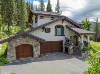 Discover luxury living in this stunning mountain retreat! This exquisite home boasts a beautiful stone facade, multiple garage spaces, and a charming covered entryway.