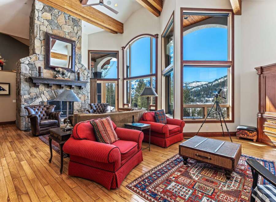 Experience luxury living in this stunning property, featuring a grand stone fireplace and expansive windows that frame breathtaking mountain views.