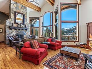 Experience luxury living in this stunning property, featuring a grand stone fireplace and expansive windows that frame breathtaking mountain views.