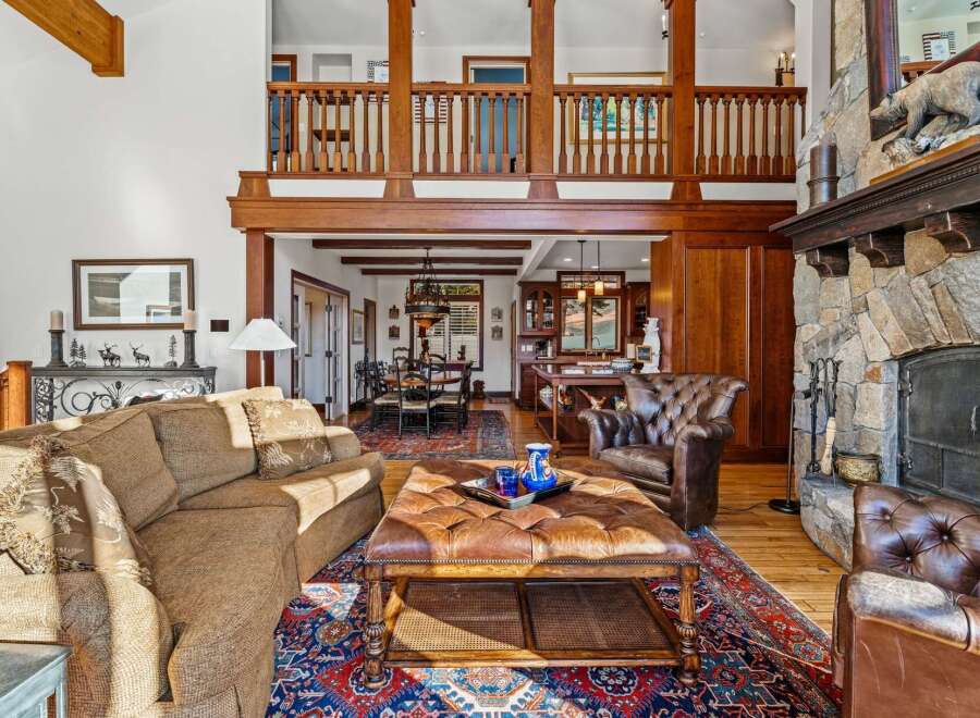 Step into luxury with this stunning property featuring a grand stone fireplace and a cozy leather armchair, perfect for relaxing evenings.