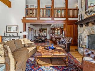 Step into luxury with this stunning property featuring a grand stone fireplace and a cozy leather armchair, perfect for relaxing evenings.
