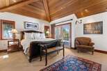 Experience luxury in this exquisite bedroom featuring a stunning wooden ceiling and a cozy seating area.