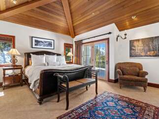 Experience luxury in this exquisite bedroom featuring a stunning wooden ceiling and a cozy seating area.
