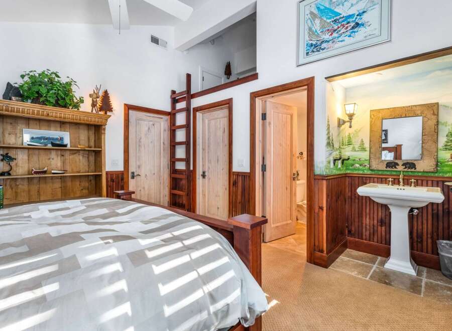 This rustic bedroom features a cozy bed, a charming wooden bookcase, and a unique ladder leading to a loft space.