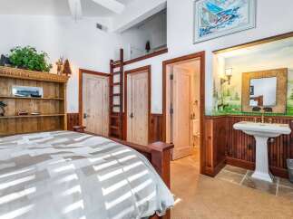 This rustic bedroom features a cozy bed, a charming wooden bookcase, and a unique ladder leading to a loft space.