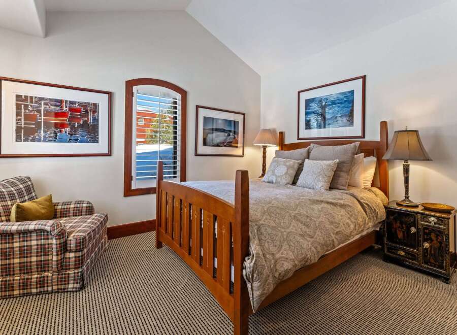 This inviting bedroom features a cozy armchair, a stylish bed, and a charming window that fills the space with natural light.