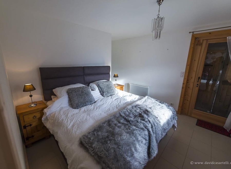 Cozy bedroom with a plush bed, soft furs, and a wooden nightstand.