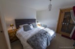 Cozy bedroom with a plush bed, soft furs, and a wooden nightstand.