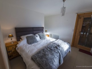 Cozy bedroom with a plush bed, soft furs, and a wooden nightstand.