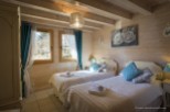 Charming twin bedroom with wooden walls and beams, featuring teal accents and white bedding.
