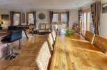 This stunning property boasts a spacious dining area with a long wooden table perfect for gatherings, complemented by comfortable wicker chairs.