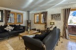 Luxurious chalet living room with a cozy fireplace, plush sofas, and large windows offering stunning views.