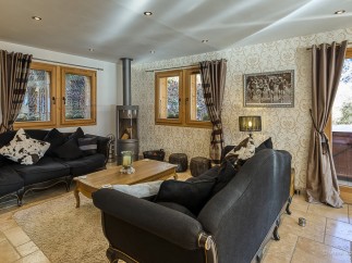 Luxurious chalet living room with a cozy fireplace, plush sofas, and large windows offering stunning views.